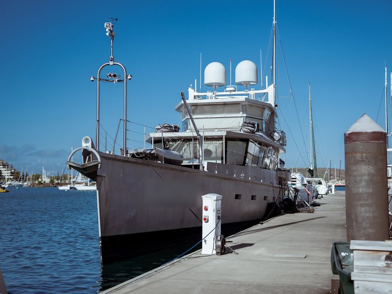 Yacht d'expédition à coque grise amarré au ponton visiteurs, à côté d'une borne eau et électricité